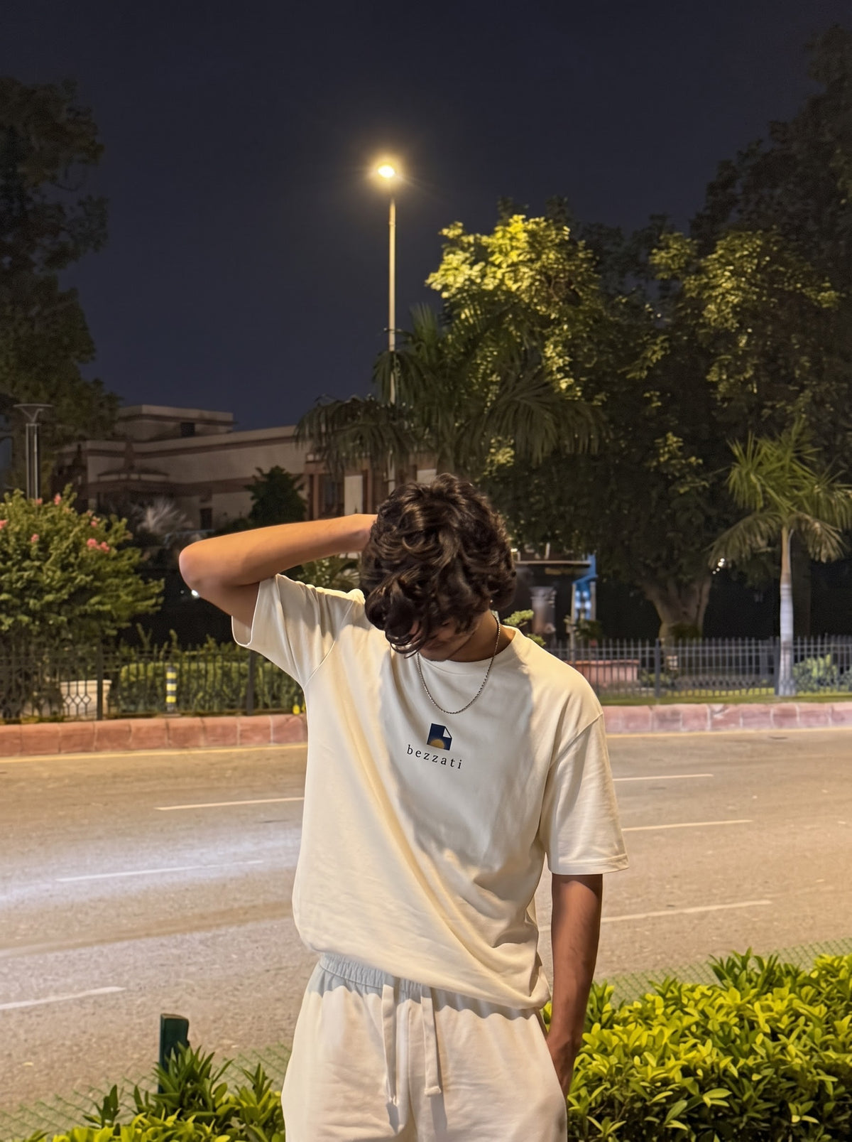 Off-white oversized t-shirt worn on a tree-lined street at night