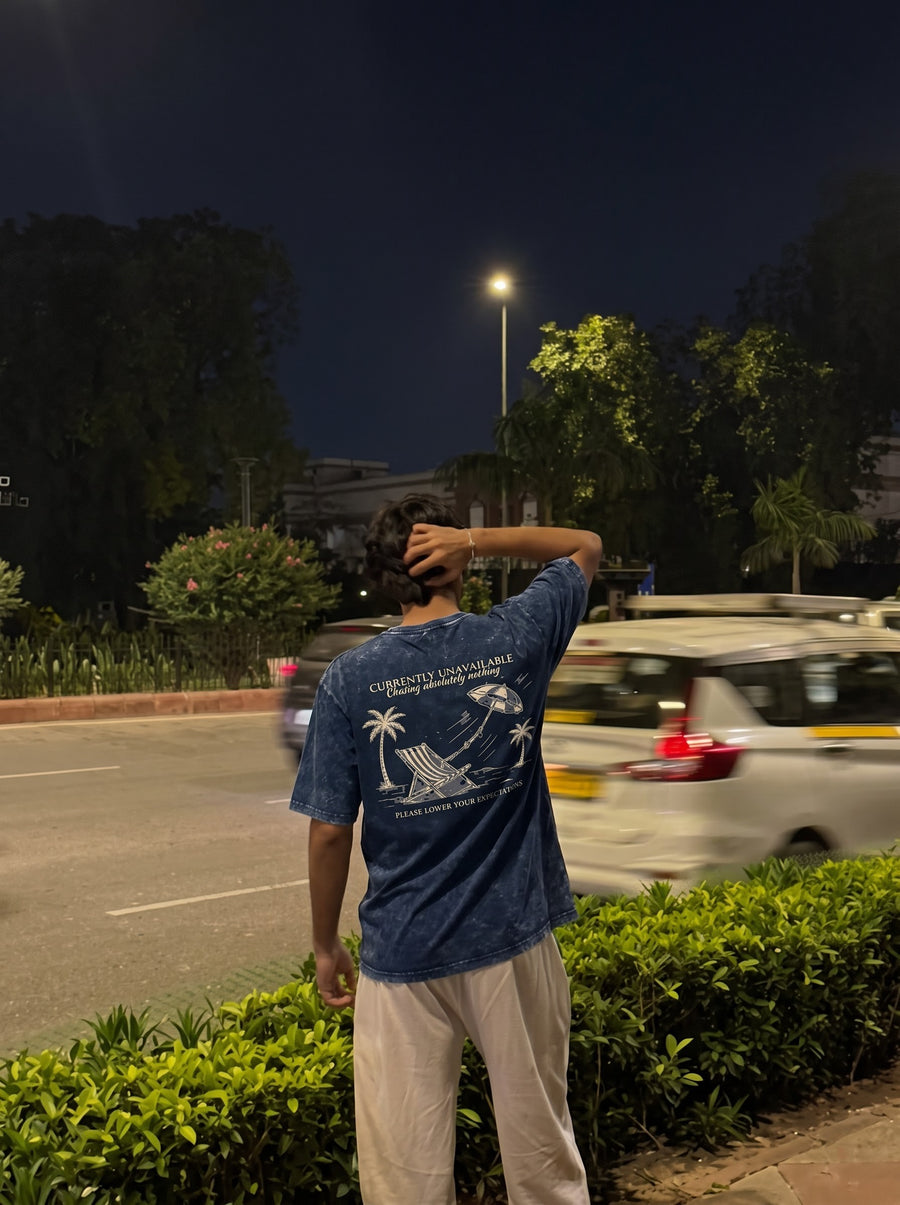 Currently Unavailable back print on a navy acid-wash t-shirt, worn at the roadside at night