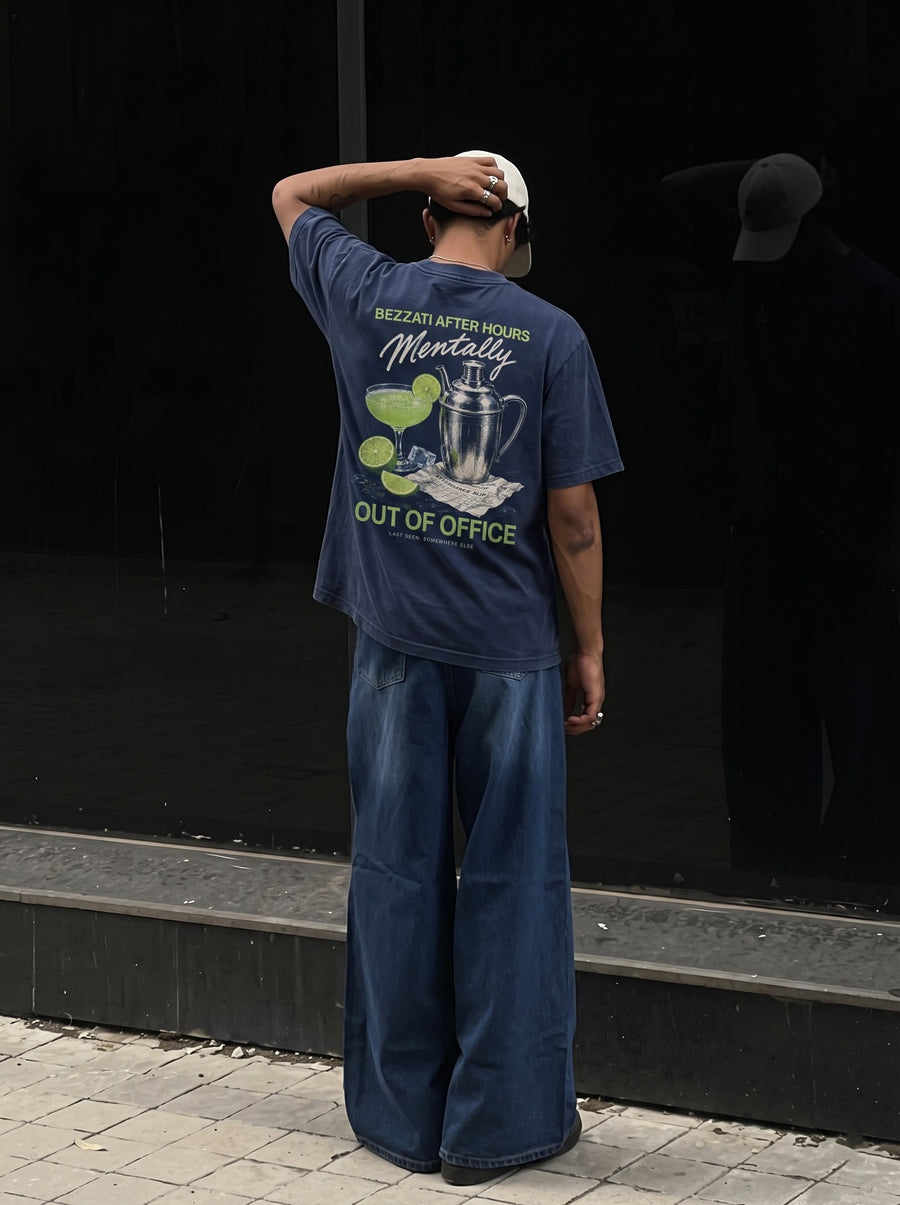 Out Of Office back print on the navy acid-wash t-shirt, worn outdoors in a courtyard