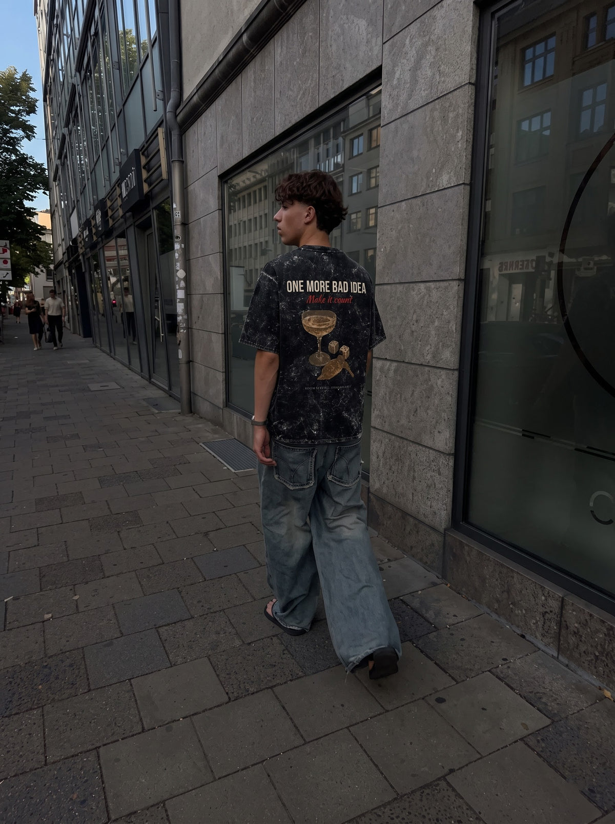 One More Bad Idea back print on the black acid-wash t-shirt, worn on a city street