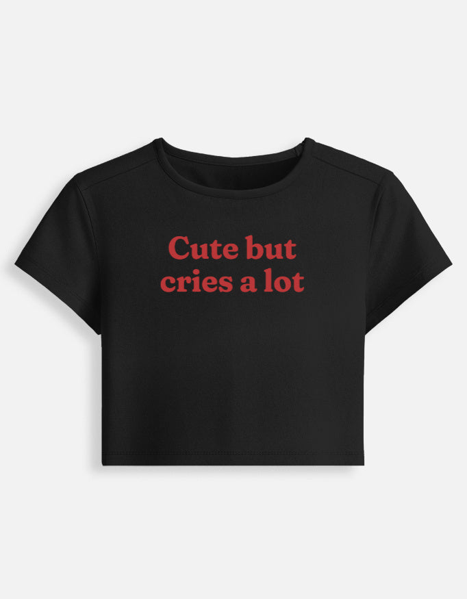 Front of the black Cute But Cries a Lot cropped baby tee: Cute but cries a lot in red serif