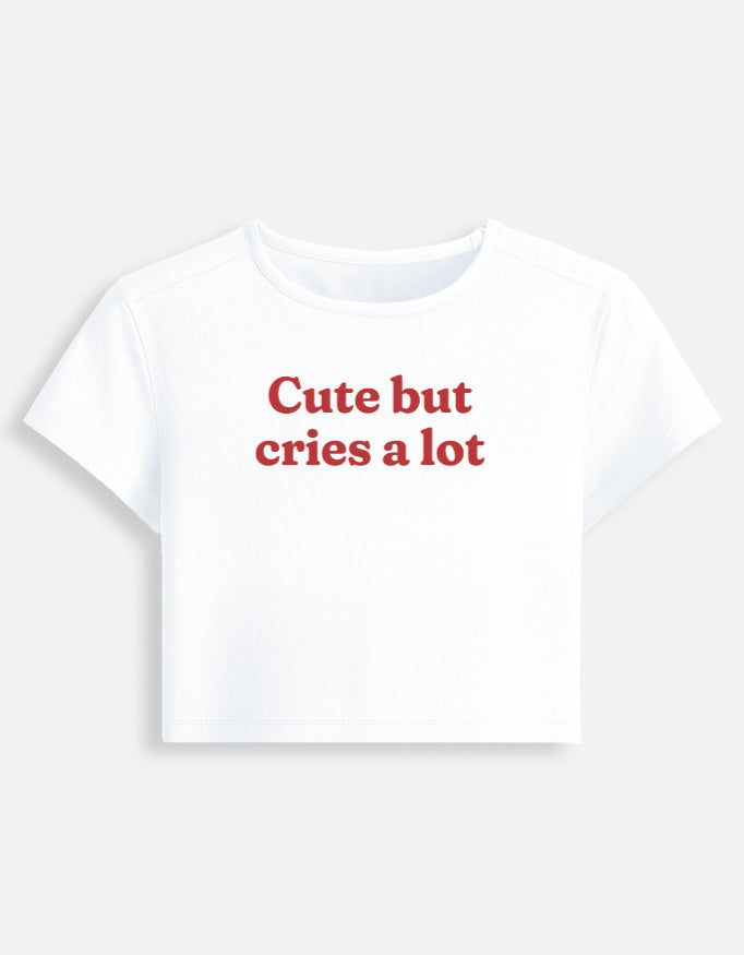 Front of the white Cute But Cries a Lot cropped baby tee: Cute but cries a lot in red serif