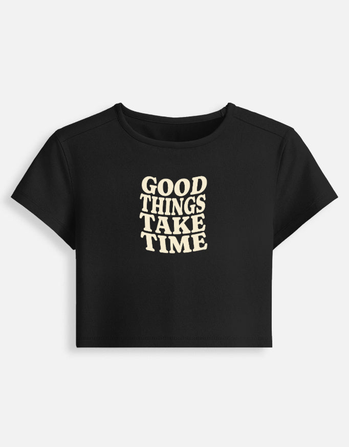 Front of the Black Good Things Take Time cropped baby tee: Good things take time in wavy cream serif capitals