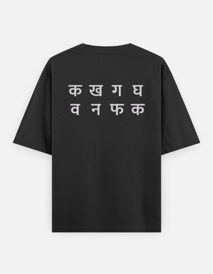 Ka Kha Ga back print on the black oversized t-shirt: two lines of off-white Devanagari letters, the top line क ख ग घ
